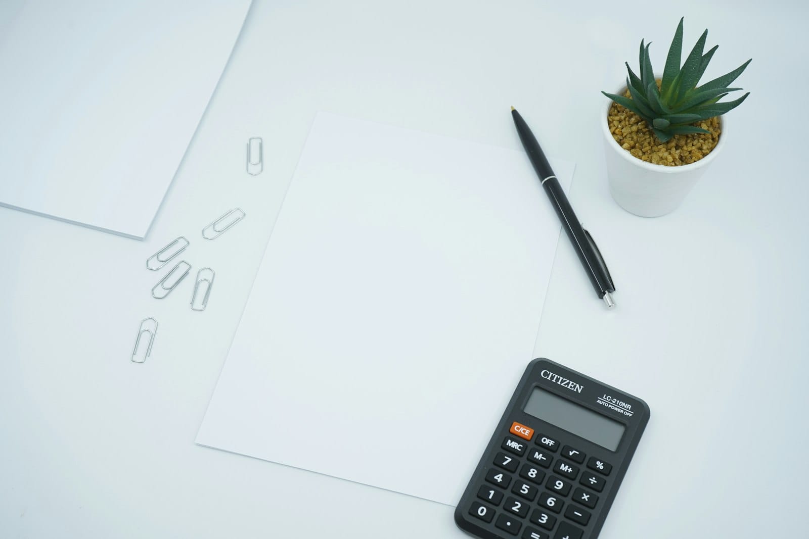 Calculator, pen, and blank paper on a desk, representing computing 14th month pay in the Philippines