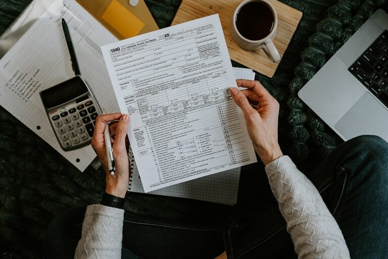 Employee reviewing a tax withholding certificate and compensation figures with a calculator, representing verification of a BIR Form 2316 in the Philippines