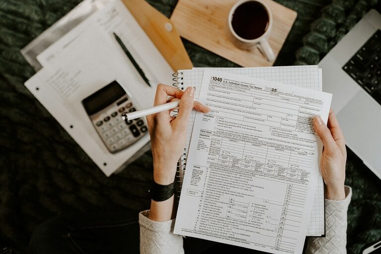 Employee checking a payslip's itemized earnings and deductions against payroll documents using a calculator