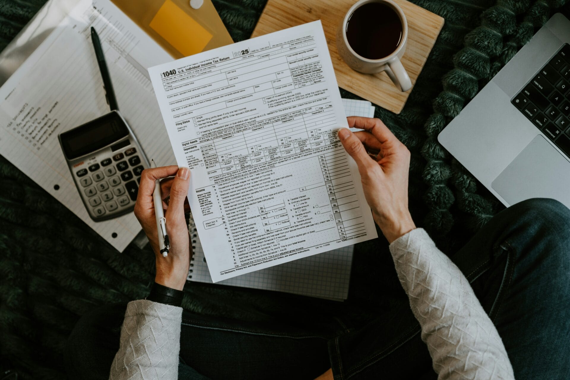 Hands holding payroll and government contribution forms with a calculator, computing PhilHealth and Pag-IBIG payroll deductions