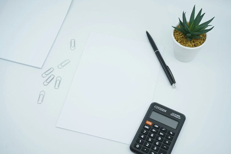 Calculator and blank worksheet on a desk used to compute an SSS monthly contribution, showing the employer and employee share calculation for a Philippine payroll