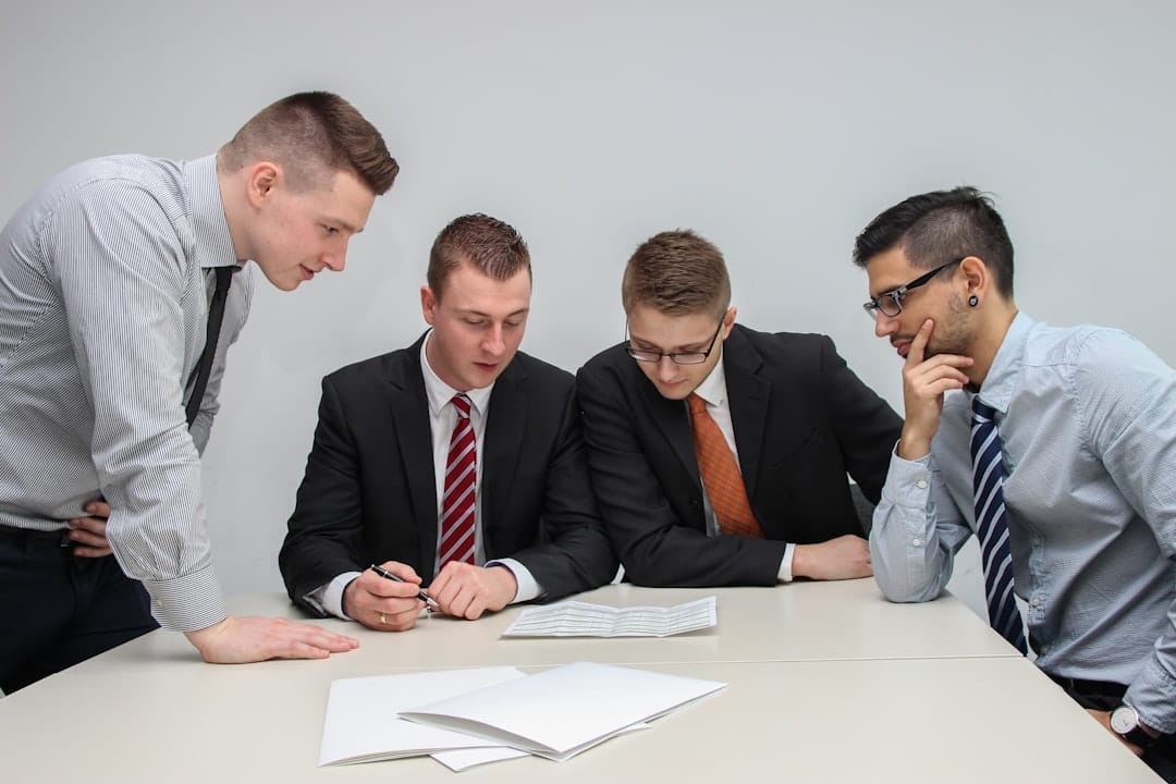 Four people at a table closely reviewing a written document together, representing employer and union negotiators going over a collective bargaining agreement proposal