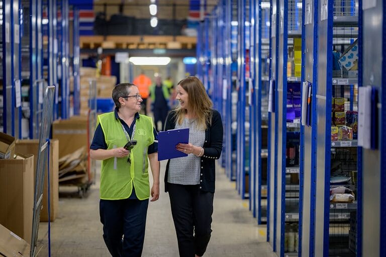 A workplace supervisor holding a clipboard while walking through a warehouse with an employee, illustrating the supervisory rank distinct from managerial and rank-and-file employees under Philippine labor law